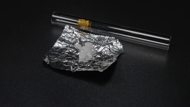 Fentanyl or crystal meth is widely used stimulant in current drug trend. Methamphetamine mixed with fentanyl as crystals in foil. Illicit substance in foil bag for transportation and sale.