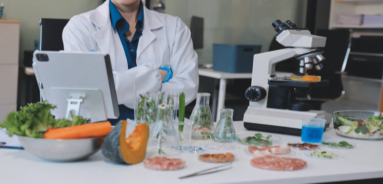 Scientists in lab coats work with plants in a modern lab, focusing on research and experimentation under bright, sterile conditions.