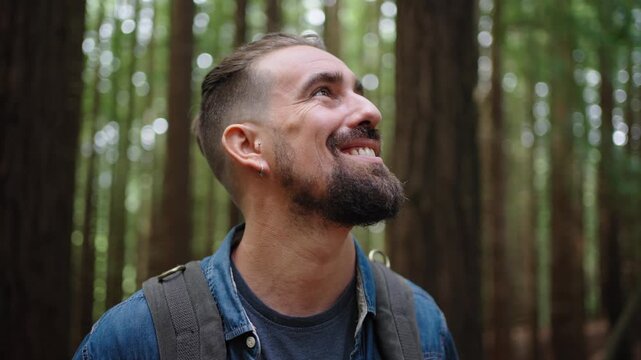 Portrait of a cheerful caucasian nomadic man outdoors in the middle of a forest, looking at camera with big smile.