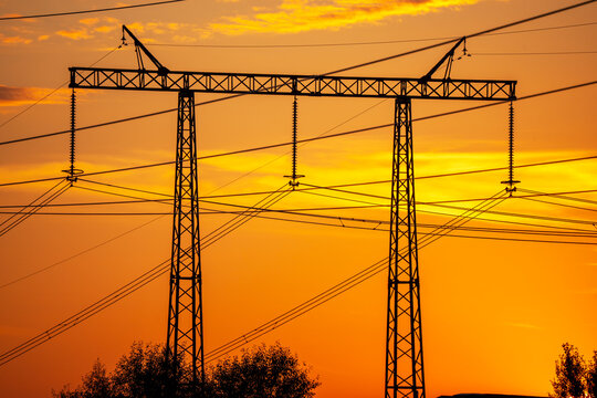 Power lines stretch across a fiery sunset sky