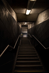 Dark underground stairway with industrial lighting and metal handrails © Wojciech Kuziów