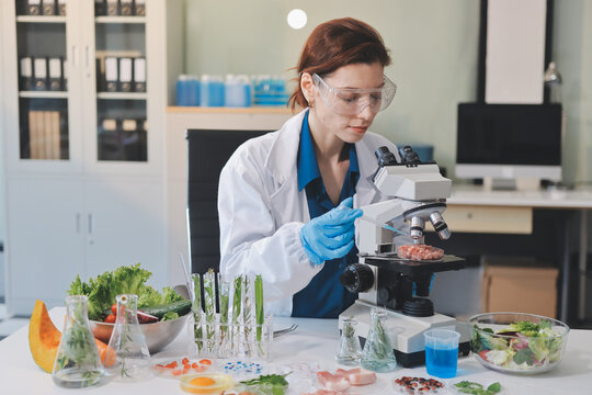 Scientists in lab coats work with plants in a modern lab, focusing on research and experimentation under bright, sterile conditions.
