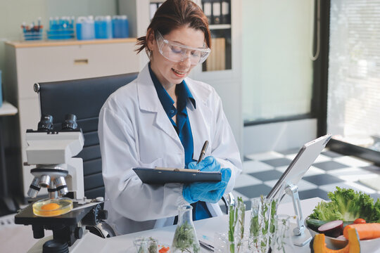 Scientists in lab coats work with plants in a modern lab, focusing on research and experimentation under bright, sterile conditions.