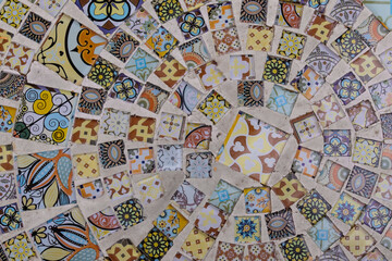 Fototapeta premium Colorful decorative ceramic mosaic made of small patterned tiles. Geometric and floral ornaments forming an abstract textured background, suitable for design, interior, and creative projects.