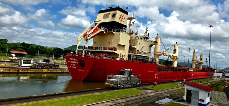 Large Cargo Ship Transiting the Panama Canal Locks; Mule Locomotive Towing Cargo Ship