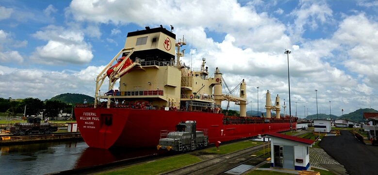 Large Cargo Ship Transiting the Panama Canal Locks; Mule Locomotive Towing Cargo Ship