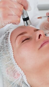 Injection-free mesotherapy or electroporation. Beautician doctor makes client adult woman forehead face therapy in beauty clinic salon. Girl skin care anti-age spa procedure. Aesthetic cosmetology
