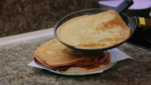 Stacking a freshly cooked golden pancake onto a plate, adding to a warm homemade pancake stack ready for breakfast