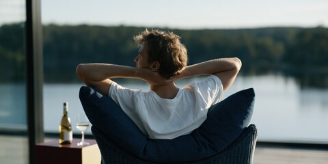 Obraz premium Man relaxing on a lakeside balcony with wine and glass for lifestyle background and calm retreat banner design