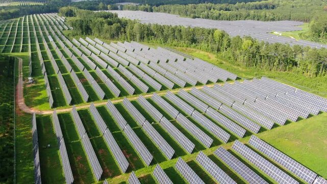 Aerial View Of A Large Solar Panel Farm Generating Clean Renewable Energy In A Forested Landscape