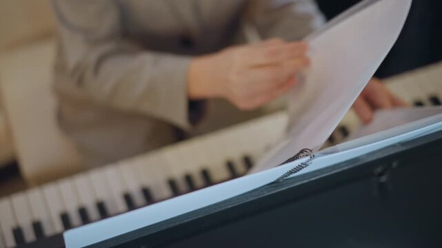 Teacher organizing sheet music carefully. Focused instructor adjusting music sheets steadily. Musicians practicing meticulously as instructor flips pages and marks music notation during rehearsal