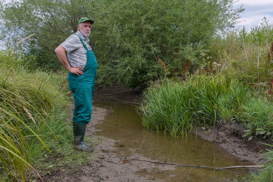 Climate change strikes mercilessly. A farmer stands by a dried-up creek bed containing only miserable remnants of water. Europe's agriculture suffers from the severe drought.