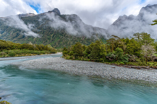 Hollyford River mit tuerkisfarbenem Wasser und Kiesbank, nebelverhangene Bergketten des Darran Massivs im Hintergrund, Fiordland National Park, Southland, Suedinsel, Neuseeland
