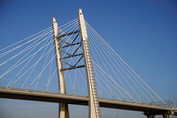 Fototapeta premium The support of a cable-stayed bridge. A cable-stayed bridge is a type of suspension bridge in which the roadway is supported by a system of steel cables fixed directly to high vertical supports.