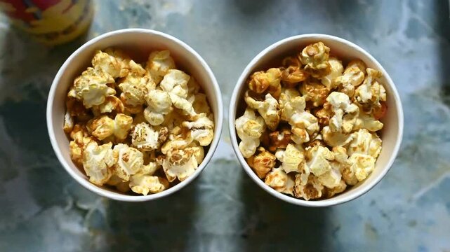 Two cups of freshly popped popcorn viewed from above, creating a cozy movie night and cinema snack concept. Food, entertainment and leisure background.