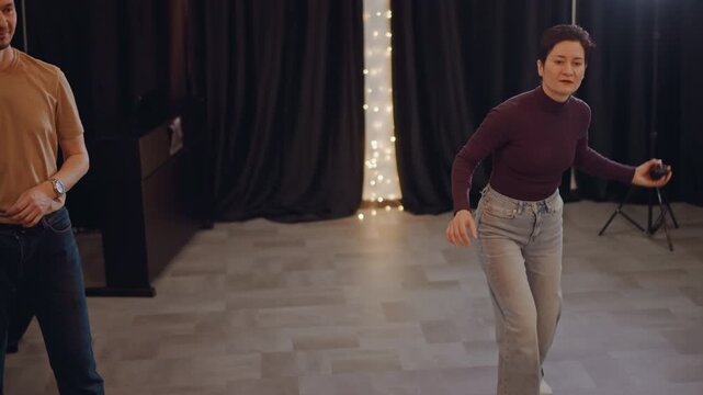 Studio vocal rehearsal with tossing ball, two adults practicing rhythm exercise, coach guiding under warm string lights, casual denim outfits, focused energy and playful interaction, microphone