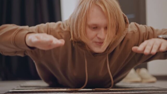 Redhaired student on floor concentrating on aural exercise and pitch detection low studio interior with carpet and muted lighting, hands on mat, intense attentive expression during music lesson
