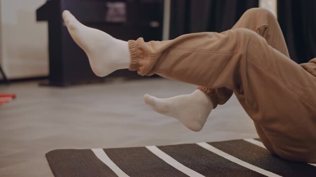 Caucasian student practicing footwork on mat, rhythmic leg lifts and core engagement in cozy studio, wearing hoodie and white socks, focused rehearsal with string lights and relaxed atmosphere,
