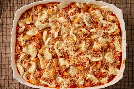 Gnocchi baked in tomato sauce with melted mozzarella and grated parmesan cheese in ceramic dish