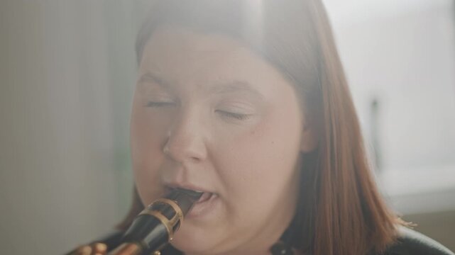 Woman playing clarinet in classroom, private lesson with focused expression, coach demonstrating embouchure and breathing, closeup mouthpiece and reed, warm natural light, student practicing tone