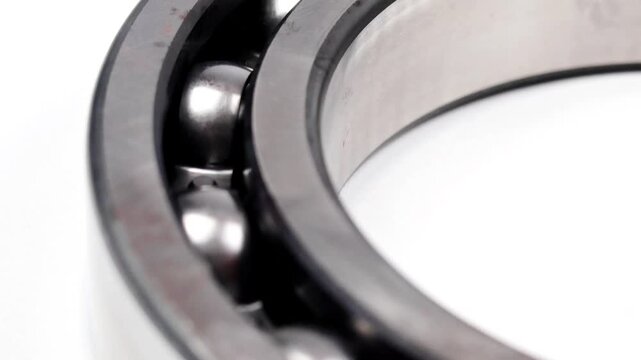 Macro close up shot of a metallic ball bearing with steel balls and races isolated on white background.