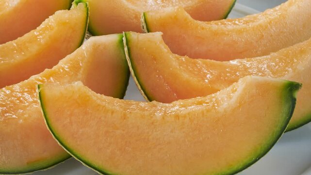 Fresh sliced cantaloupe melon showcasing vibrant orange flesh and pale green rind in detailed close-up