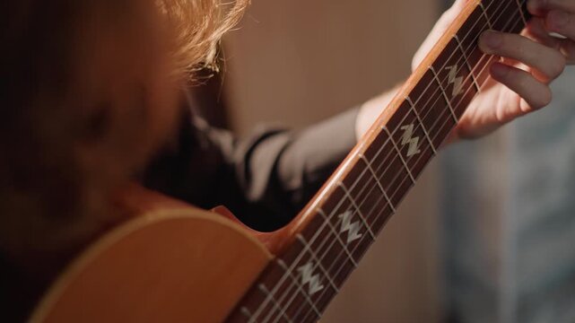 Closeup of guitar playing. Teacher guides guitarist during intimate fingerstyle practice session. Detailed closeup of musician demonstrating accurate fretting under studio lighting conditions