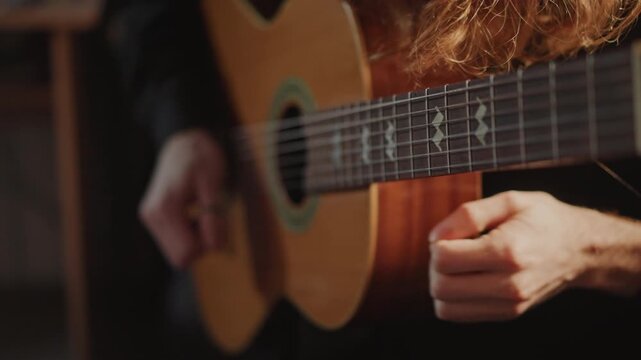 Closeup fingerboard fingerstyle left hand fretting, longhaired guitarist practicing scales and arpeggios under warm low light, right hand plucking, technical focus, tutor guidance, intimate rehearsal
