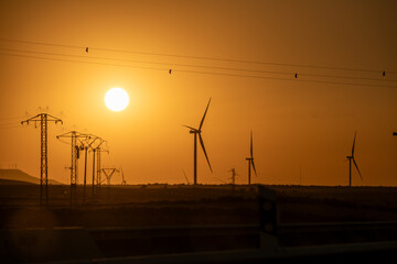 Wind Farm and Power Lines Silhouetted Against Sunset Sky © edu_mngs