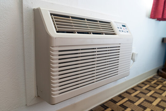 A wall-mounted HVAC air conditioning and heating unit installed in a hotel or motel room, showcasing indoor climate control, ventilation,and modern accommodation amenities.
