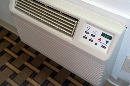 A wall-mounted HVAC air conditioning and heating unit installed in a hotel or motel room, showcasing indoor climate control, ventilation,and modern accommodation amenities.