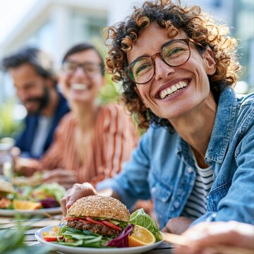 Friends enjoy a meal at an outdoor table with burgers and salad