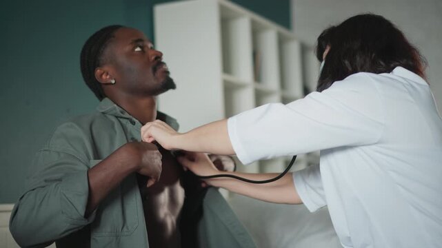 Male patient chest exam in bedroom by nurse using stethoscope, tense atmosphere with quick assessment, shirt pulled aside, nurse listening to lungs, checking vitals, paramedic style response