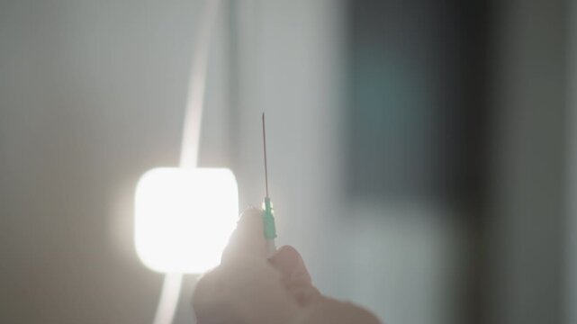 Sterile technique ensuring secure connection. Hands carefully align needle with intravenous tube during procedure. Health professional maintains steady grip for safe infusion link during operation