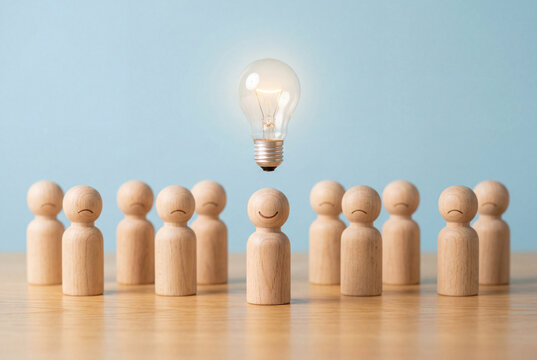 Smiling wooden peg figure with a glowing lightbulb standing ahead of frowning figures