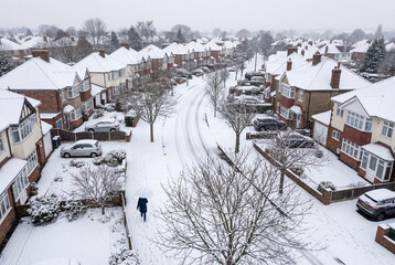 Fototapeta premium Aerial view of suburban street and houses covered in winter snow