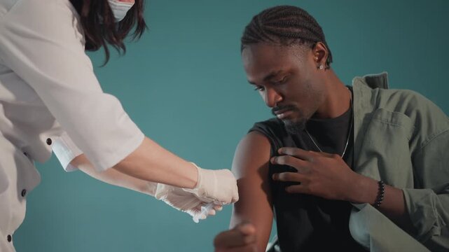 Nurse provides vaccination. Healthcare worker offers calm immunization session. Compassionate nurse carefully guides male patient through vaccination in outreach setting with reassurance
