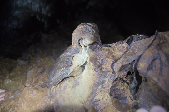 Stalagmites and rock mineral deposits on a cavern wall illuminated by a flashlight