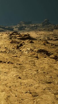Rocks cover the surface of an alien planet. Shadows stretch across the landscape. A faint light source illuminates parts of the rocky terrain. The sky shows deep colors above.