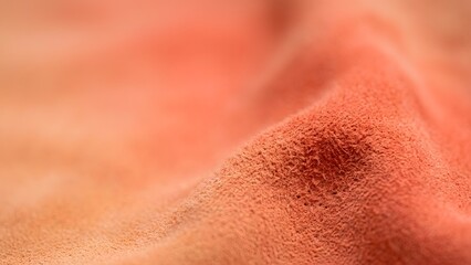 Fototapeta premium Close-up macro shot of a soft textured fabric in warm orange and peach tones, with gentle folds and a shallow depth of field.