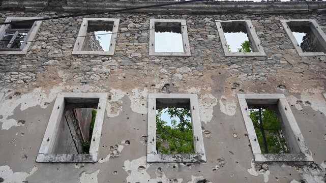 Burned house destroyed by artillery in war. Ruined home showing consequences of war. Devastated building after military attack.
