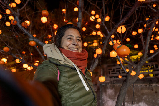 Happy woman taking selfie among orange lantern tree in Datong