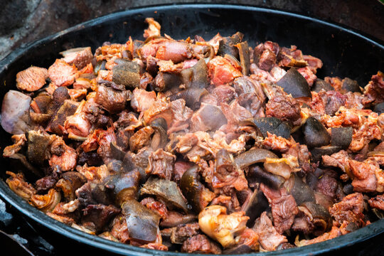 Close-up of spicy Nigerian asun, made from roasted goat meat and seasoned with peppers, shown in the pot used for its preparation