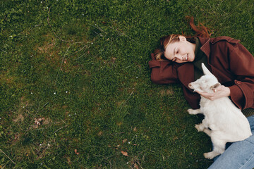 Obraz premium Relaxed woman lying on grass with goat kid, enjoying a peaceful outdoor moment, casual attire, sunlight, friendship, gentle bond between human and animal, serene scene, happiness, natural setting,