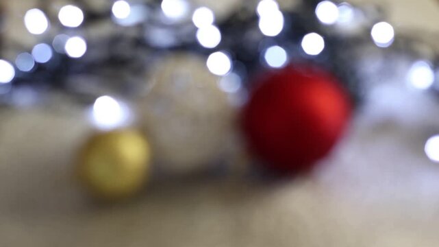 Una toma de cerca de bolas de navidad de varios colores con luces de navidad con desenfoque en un fondo negro. 