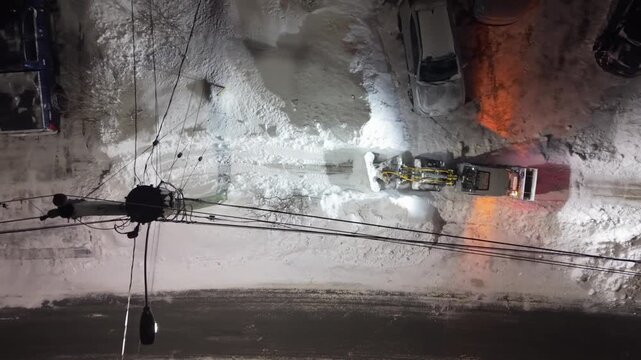 Aerial footage captures a snowplow diligently working to clear the snow-covered streets of Beachville during a nighttime scene following the recent storm in Halifax