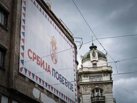 BELGRADE, SERBIA - JUNE 13, 2026: A large "Srbija pobedjuje" political banner with Serbia's coat of arms covers a building facade in central Belgrade, on SNS campaign messaging and propaganda.