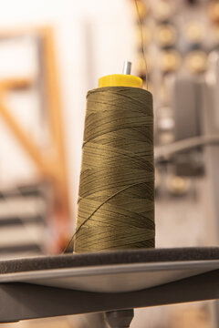 close up of a thread spool beside manufacturing equipment