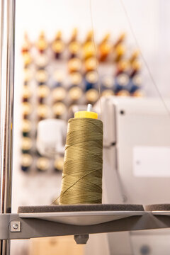 A spool of sewing thread on a varied background, with space for text nearby.