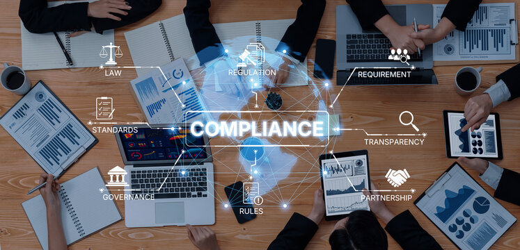 A business meeting focused on compliance strategies using technology tools, featuring charts and documents on a conference table among professionals discussing regulations and standards. Trope